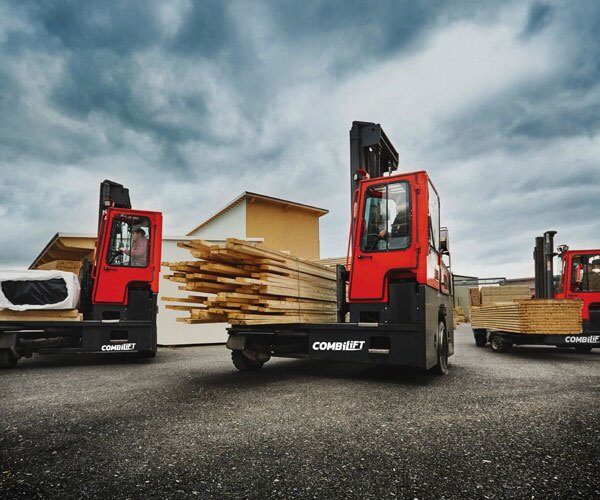 Combilift forklifts for sale transporting long timber loads efficiently at an outdoor worksite